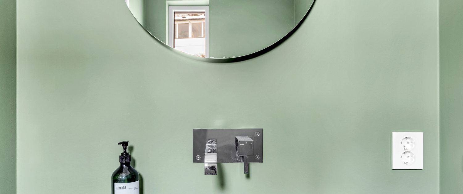 Bad med grønn vegg, sort servant og rundt speil